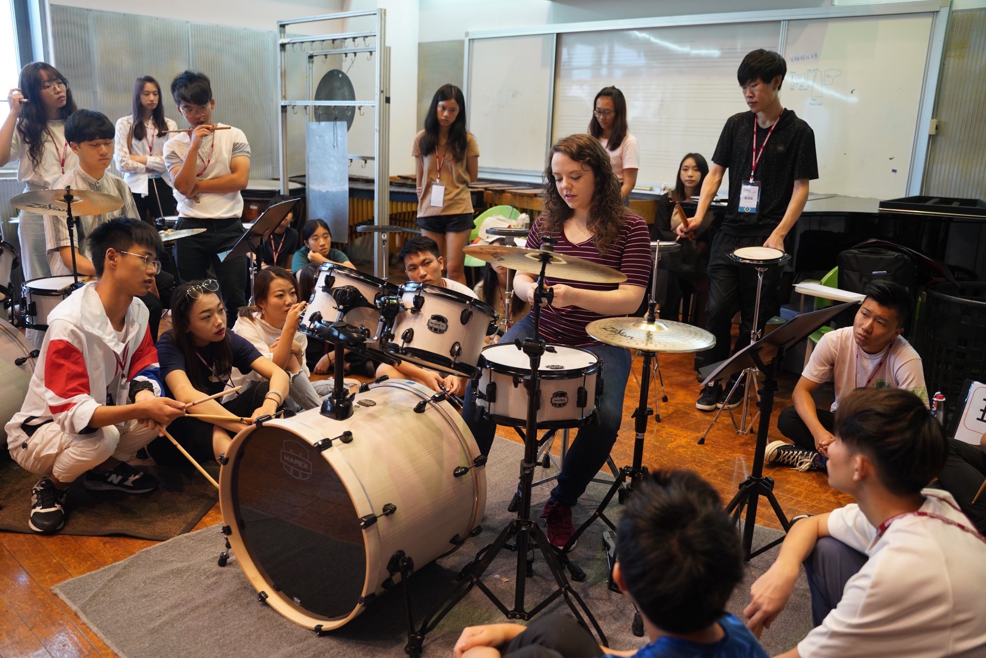 Lindsay Artkop teaching private drum clinic at her drum set. Students Watch and ask questions